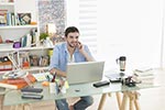 Mann sitzt vor Laptop in Arbeitszimmer
